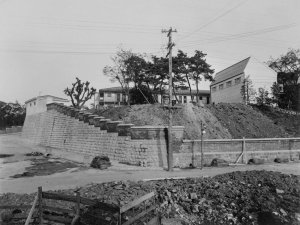 Retaining wall repairs at the north-west corner of the compound, with garages, staff village and squash court beyond.