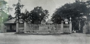 Road entrance to compound, with seated Queen Victoria,1900s.